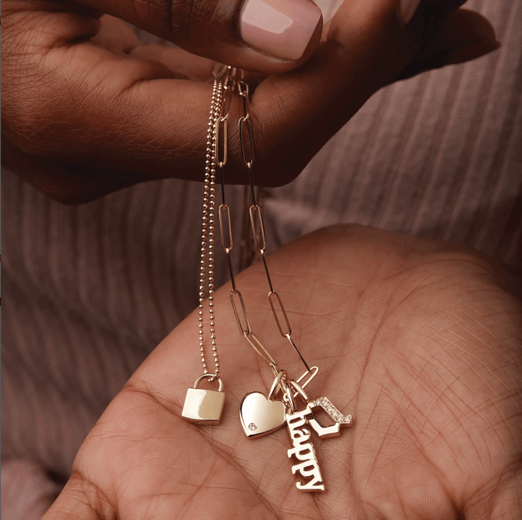 woman holding gold letter charm necklaces in her hand