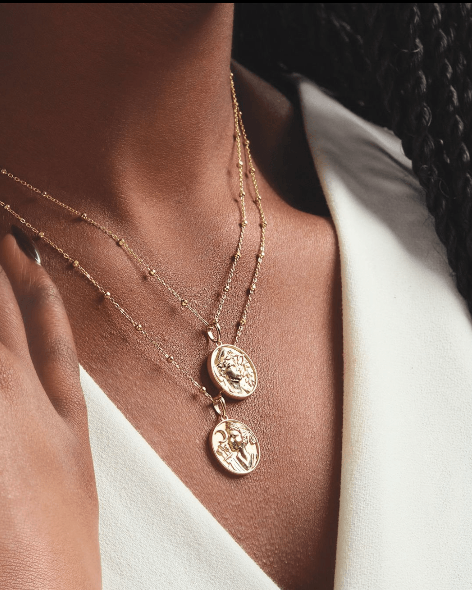 gold medallion necklaces on women with white blouse